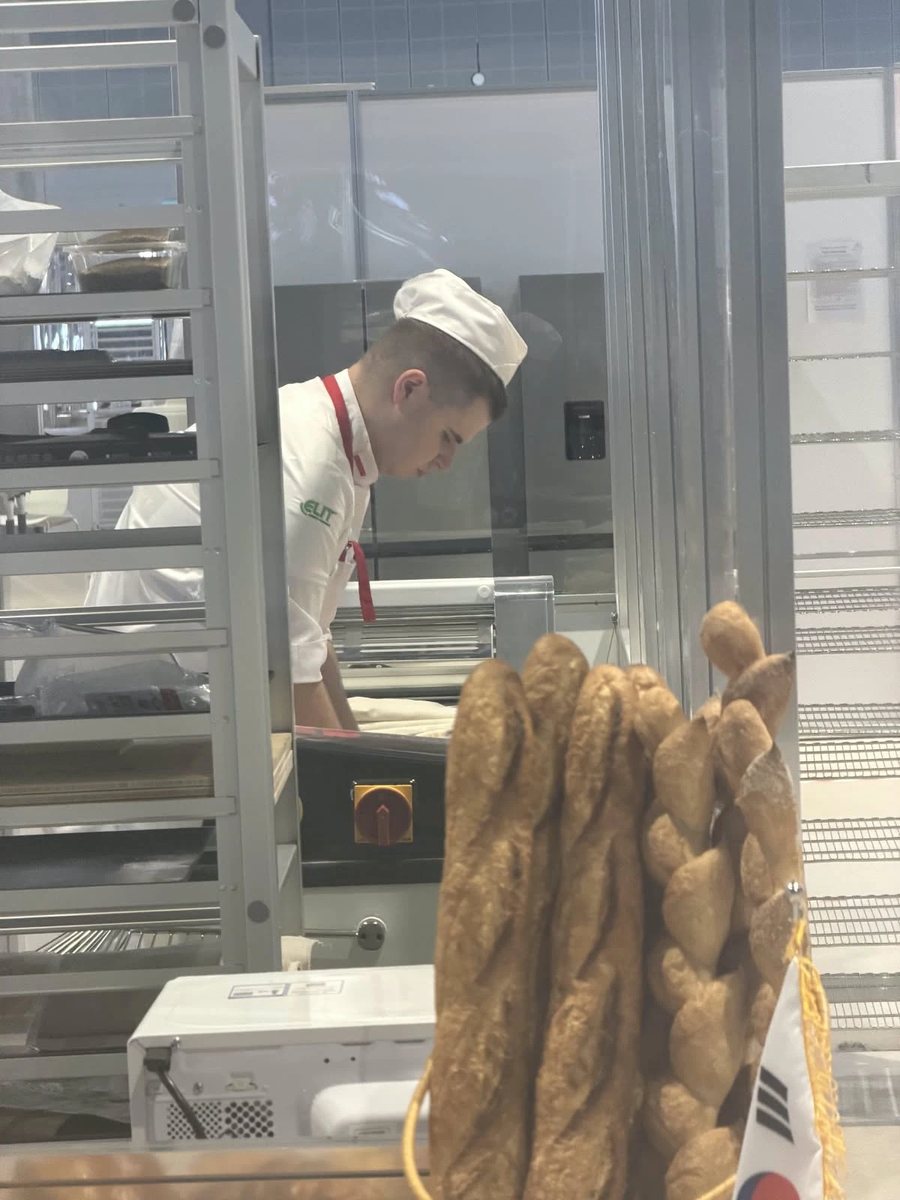 Patryk Podsiadło w kurtce z logo ELIT podczas pracy na stanowisku piekarskim WorldSkills Shanghai 2026