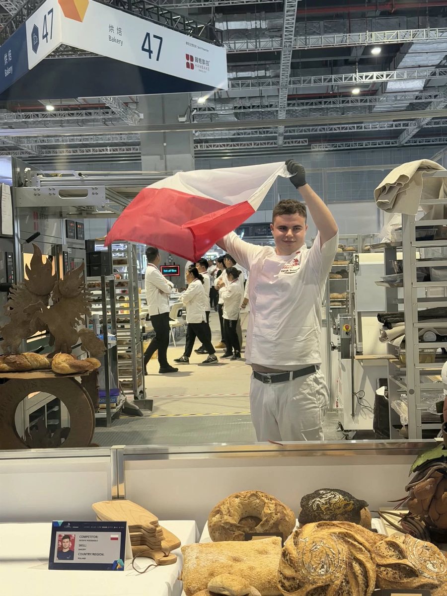 Patryk Podsiadło z flagą Polski na stanowisku konkursu piekarskiego WorldSkills Shanghai 2026
